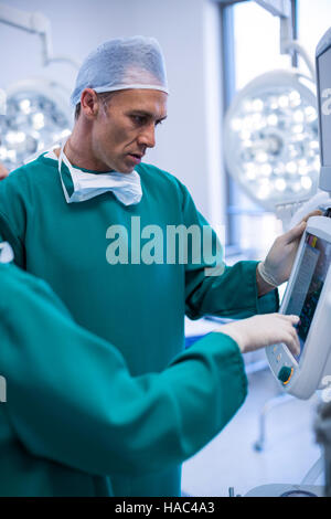 Chirurgen diskutieren einen Bericht über die chirurgische Monitor im OP-Saal Stockfoto