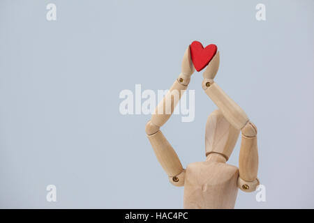 Holz Figur hält ein rotes Herz an der Spitze Stockfoto