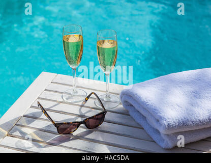 Zwei Gläser Champagner auf einem weißen Holztisch neben dem Pool im Sommer. Stockfoto