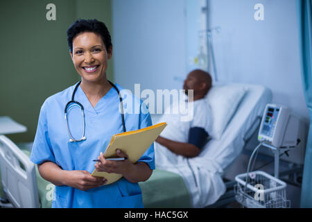 Porträt von Krankenschwester stehend mit Datei im Bezirk Stockfoto