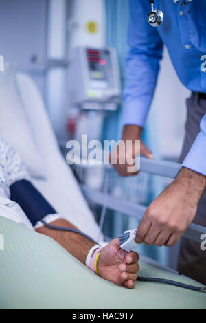 Herr Doktor putting Herzfrequenz-Sensor am Finger des Patienten Stockfoto