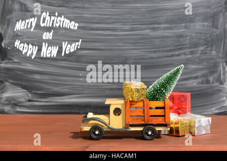 Spielzeug-LKW trägt Geschenke und einen Weihnachtsbaum. Weihnachten Hintergrund Stockfoto