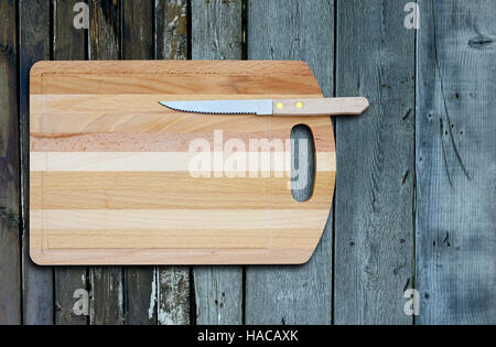 Leere Bambus Schneidbrett und Messer auf einem alten Holztisch für Warenpräsentation. Ansicht von oben Stockfoto