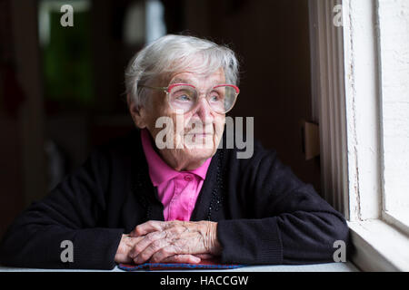 Eine ältere Frau sitzt am Fenster. Stockfoto