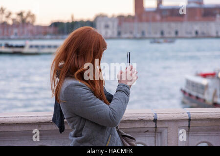 Flache Schärfentiefe, (Hand und Telefon) Ginger dunkelhaarige Frau mit Handy zu fotografieren, Venedig, Italien. Stockfoto