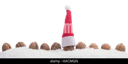 Reihe von Walnüssen im Schnee mit Weihnachtsmütze s auf weißem Hintergrund Stockfoto