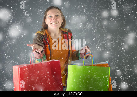 Glückliche Frau mit Einkaufstüten über Schnee Hintergrund. Einkauf, Verkauf, Weihnachten und Feiertage Konzept. Stockfoto