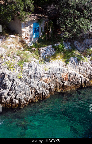 Kleines altes Steinhaus auf Klippe am tiefblauen Adria in Kroatien Stockfoto