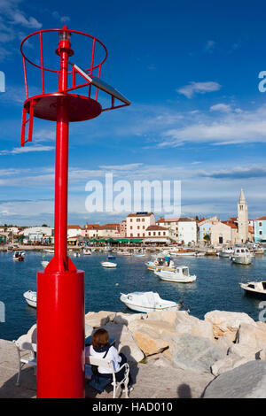 Roten Leuchtturm mit Solar-Panel und Frau sitzen auf Bank im Hafen von Fazana in Kroatien Stockfoto