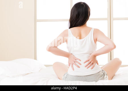 asiatische Frau leidet unter Rückenschmerzen Rückenschmerzen, Wirbelsäule oder niedriger Problem zurück. Schlafzimmer-Hintergrund Stockfoto