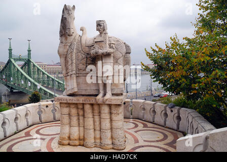 Statue der Szent István Király, König Stephan von Ungarn am Gellértberg. Auf Backgriund der Szabadság híd (in englischer Sprache: Freiheitsbrücke oder Freiheitsbrücke) in Budapest, Ungarn, verbindet Buda und Pest über die Donau. Es ist die dritte südlichsten öffentliche Straßenbrücke in Budapest, und befindet sich am südlichen Ende des Stadtzentrums. Es hieß ursprünglich Ferenc József híd (Franz-Joseph-Brücke). Stockfoto