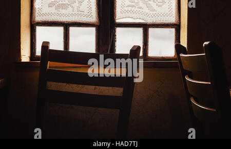 Detailansicht eines alten Holzfenster und Stuhl davor. Stockfoto