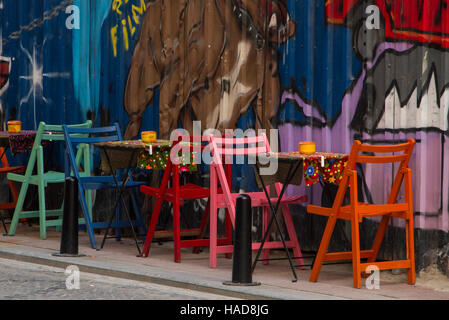 Straßencafé mit verschiedenen Farben Tischen und Stühlen und Wand mit Graffiti Stockfoto