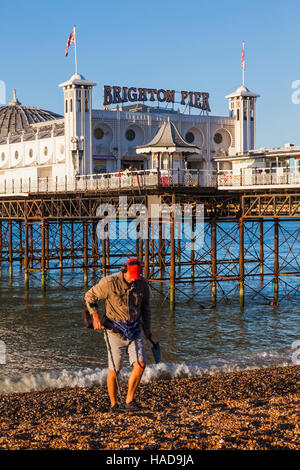 England, East Sussex, Brighton, Mann mit Metalldetektor am Strand und Pier von Brighton Stockfoto