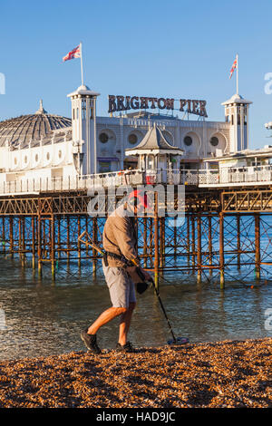 England, East Sussex, Brighton, Mann mit Metalldetektor am Strand und Pier von Brighton Stockfoto