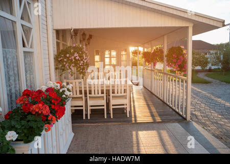 Blumen hängen auf einer Veranda. Weiße farbige und Sonnenlicht. Zeit nach Hause. Denken Sie daran, diejenigen, die Sie erwarten. Stockfoto