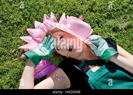 Weibliche Gärtner mit Papier Blume und Strohhut im Sonnenlicht. Stockfoto