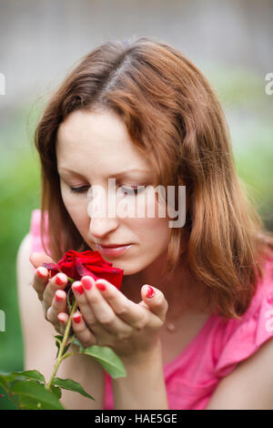 Porträt der jungen Frau duftende Rosen im Garten Stockfoto