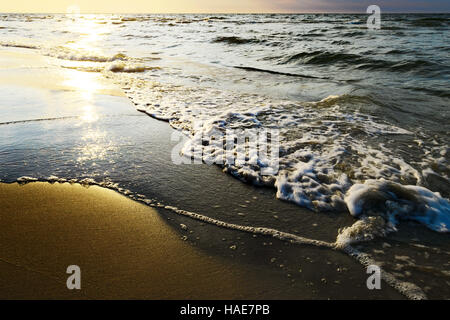 Wellen brechen sich am Strand bei Sonnenuntergang. Ostsee, Pommern, Nordpolen. Stockfoto