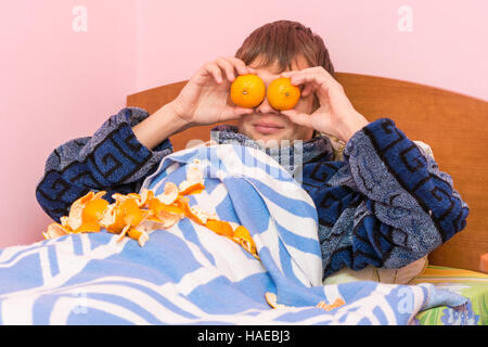 Mann liegt im Bett und lustige Mandarinen schloss die Augen Stockfoto