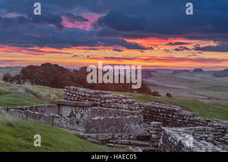 Römisches Kastell Housesteads, Hadrians Wall - bleibt ein Teil der Latrinen, gesehen in der Morgendämmerung mit einem spektakulären Sonnenaufgang Stockfoto