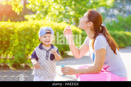 Mutter mit einen kleinen Sohn lachend im freien blubbern. Spaziergang in der Natur mit Sonnenlicht. Stockfoto