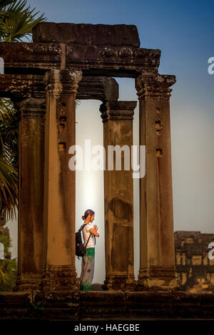 Ein Tourist steht im Gebet mit gefalteten Händen beobachten Morgen Sonnenaufgang an der Tempelanlage Angkor Wat, Siem Reap, Kambodscha. Stockfoto