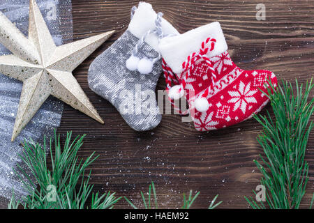 Weihnachten-Zusammensetzung von zwei gestrickte Socken und Xmas Baum Zweige und Sterne Ornament auf hölzernen Hintergrund Stockfoto