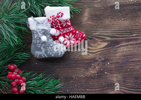 Weihnachten-Zusammensetzung der zwei gestrickte Socken, Rowan Beeren und Weihnachtsbaum Äste auf hölzernen Hintergrund Stockfoto