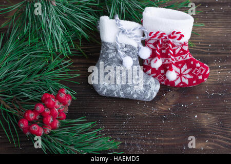 Weihnachten-Zusammensetzung der zwei gestrickte Socken, Rowan Beeren und Weihnachtsbaum Äste auf hölzernen Hintergrund Stockfoto