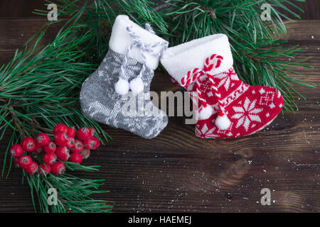 Weihnachten-Zusammensetzung der zwei gestrickte Socken, Rowan Beeren und Weihnachtsbaum Äste auf hölzernen Hintergrund Stockfoto