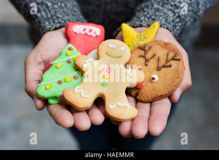 Closeup von einem kaukasischen Jüngling mit einem Haufen von Weihnachtsplätzchen mit verschiedenen Formen und Farben in seinen Händen Stockfoto