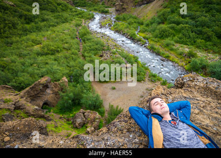 Glücklich Jüngling liegen am Rand der Klippe in der Nähe von Glymur Wasserfall in Island. Stockfoto