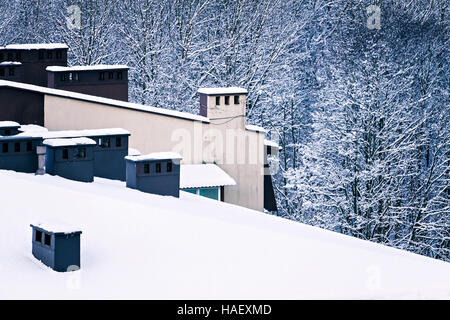 Winter-Ansicht von oben. Mehrfamilienhaus-Dach mit Schornsteinen mit Schnee bedeckt Stockfoto
