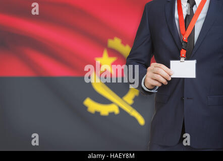 Geschäftsmann hält Namensschild Karte auf ein Schlüsselband mit einer Flagge auf Hintergrund - Angola Stockfoto