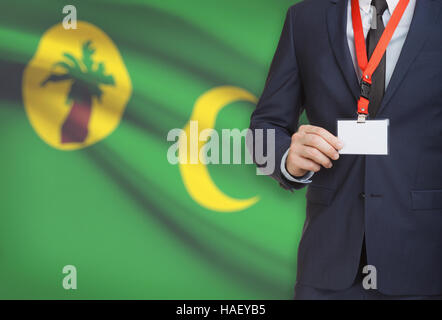 Geschäftsmann hält Namensschild Karte auf ein Schlüsselband mit einer Flagge auf Hintergrund - Cocos (Keeling) Inseln Stockfoto