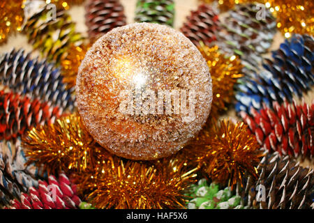 Weihnachten Zusammensetzung aus lackiertem Tannenzapfen, Lametta und ein glänzendes Gold Kugel in der Mitte. Stockfoto