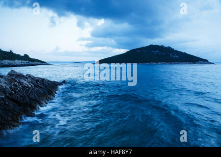 Wellen, die wie ein Sturm bewegt sich Weg über Veli Osir und Mali Osir Inseln in der Morgendämmerung, gesehen vom Zaosiri Strand, Cunski auf Insel Losinj, Kroatien. Stockfoto