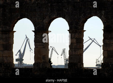 Hafenkrane durch Bögen der alten römischen Amphitheater, die Arena in Pula, Istrien, Kroatien, Europa Stockfoto