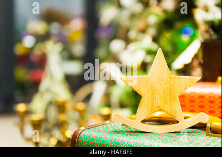 Weihnachten Fir Tree Toys alte hölzerne Sterne es auf eine Retro-Koffer brennende Kerzen, Boxen, Kugeln, Pinienzapfen, Walnüsse, Branchesin Hintergrund andere Dekorationen und Girlanden steht. Textfreiraum. Stockfoto