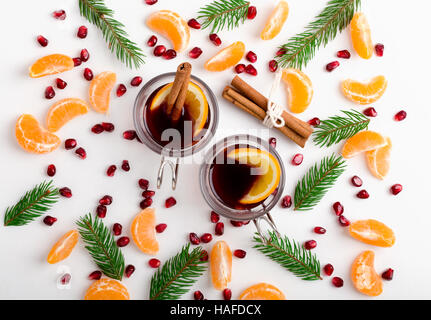 Rahmen der Granatapfel Samen, Mandarinen und Zweigen Baum mit zwei Gläsern von heißem Glühwein mit Orangen und Gewürzen. Handgemachte Dekoration Weihnachten Stockfoto