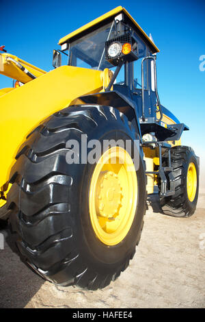 Leuchtend gelbe Traktor auf dem Hintergrund des blauen Himmels an einem sonnigen Tag Stockfoto