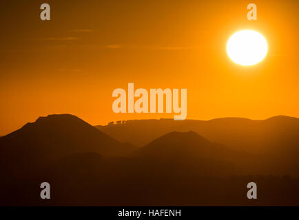 Die Konturen der Stretton Hügel hervorgehoben durch die untergehende Sonne, gesehen vom Wrekin, Shropshire, England, UK. Stockfoto