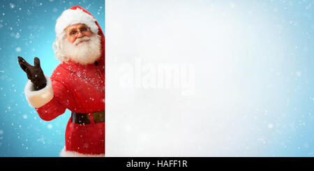 Lächelnden Weihnachtsmann Banner mit Leerzeichen für Ihr Text halten. Frohe Weihnachten & Silvester-Konzept. Hautnah auf blauen Hintergrund jedoch unscharf. Stockfoto