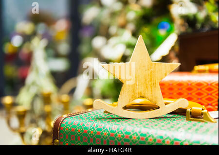 Weihnachten Fir Tree Toys alte hölzerne Sterne es auf eine Retro-Koffer brennende Kerzen, Boxen, Kugeln, Pinienzapfen, Walnüsse, Branchesin Hintergrund andere Dekorationen und Girlanden steht. Textfreiraum. Stockfoto