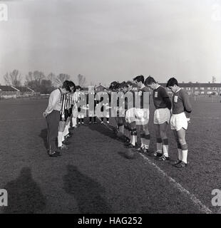 1965, historische, zwei amateur Fußball Mannschaften stehen einander gegenüber auf dem Spielfeld, mit Neigten 2 Minuten Stille vor dem Spiel auf das Gedenken Sonntag zu beobachten, als Zeichen des Respekts und zu Ehren der Die menwho kämpfte tapfer und im WW1 enthalten. Stockfoto