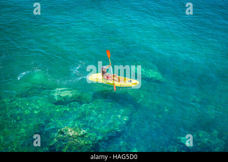 Man Kanu Meer, Blick auf einen Mann paddeln einen kleinen gelben Kanu über den Hafen von Ortigia, Sizilien. Stockfoto