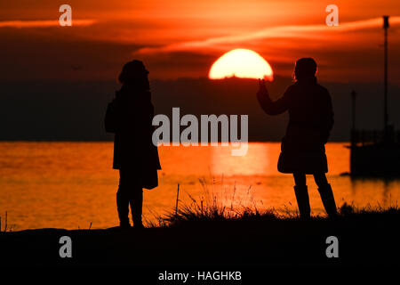 Friedrichshafen, Deutschland. 1. Dezember 2016. Zwei Frauen beobachten den Sonnenuntergang über dem Bodensee in Friedrichshafen, Deutschland, 1. Dezember 2016. Foto: Felix Kästle/Dpa/Alamy Live News Stockfoto