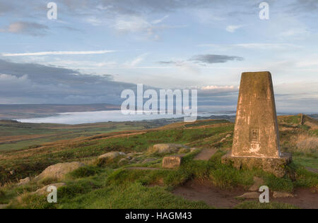 Trig Punkt auf Winshields Klippen, Hadrianswall, Northumberland mit entfernten Dawn Nebel über Haltwhistle und das South Tyne-Tal Stockfoto