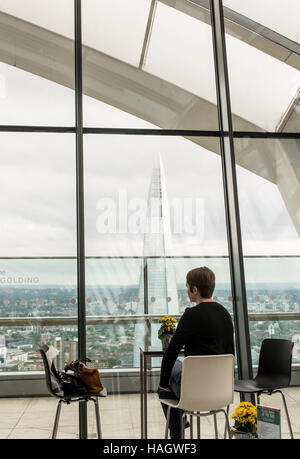 Frau allein an einem Tisch sitzen, an einem kühlen bar genießen Sie die spektakuläre Aussicht auf die Scherbe aus der Sky Garden Stockfoto